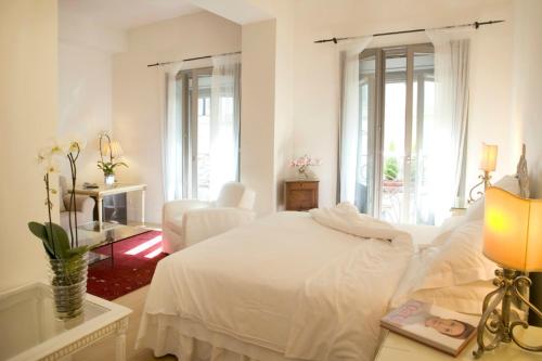 a white bedroom with a bed and a table with a lamp at Antica Locanda Dei Mercanti in Milan