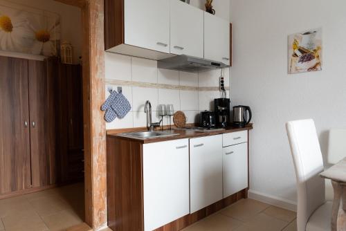 uma cozinha com armários brancos e um lavatório em Ferienwohnung am Kurpark Ostrau em Bad Schandau