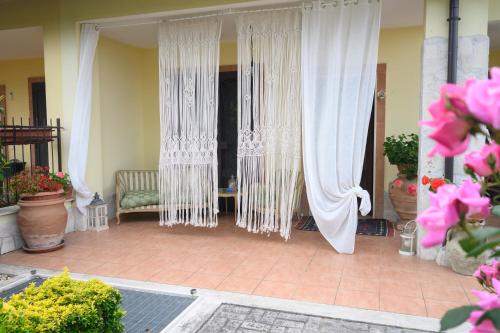 um alpendre com cortinas brancas, uma cadeira e flores em A casa di Lu' elegant room em Monterotondo