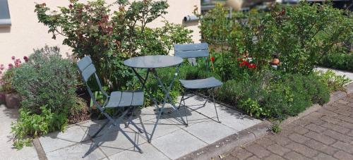 two chairs and a table in a garden at Ferienwohnung Freitag in Vendersheim