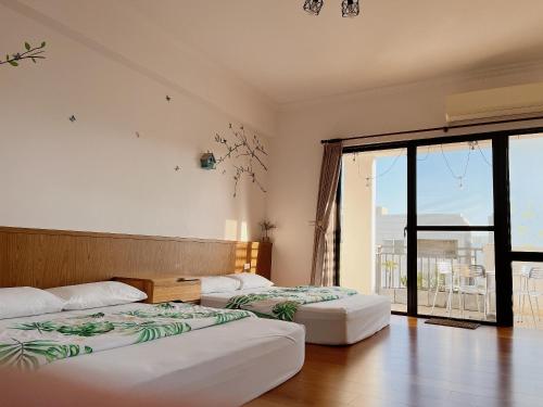 two beds in a room with a large window at 木子家民宿 in Magong