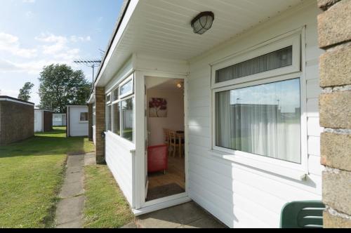 a white house with a door and a window at 82, Sunbeach Holiday Park, California Rd, California, Great Yarmouth NR29 3QL in Scratby