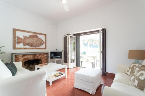 a living room with white furniture and a fireplace at Villa Jacarandá in Cascais