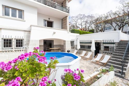 a villa with a swimming pool and flowers at Villa Jacarandá in Cascais