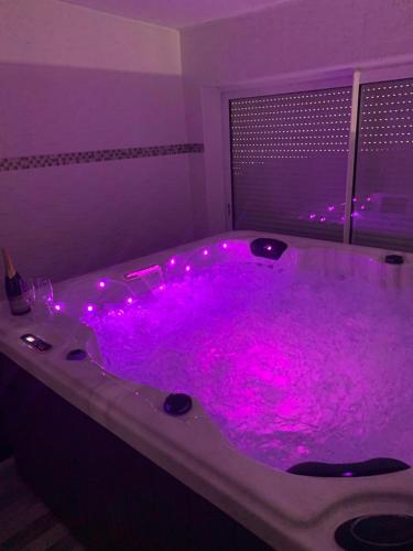 een paars bad met roze verlichting in een kamer bij Chez Sophie in Altviller