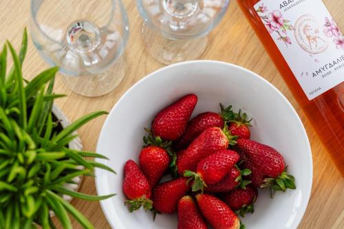 a bowl of strawberries on a table with wine glasses at Orkos Naxian Wave 3 in Mikri Vigla