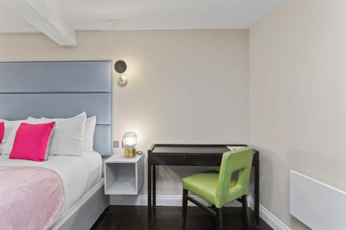 a bedroom with a bed and a desk with a green chair at London's boutique studio in London