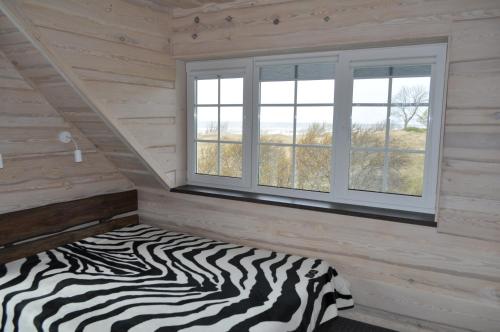 a zebra print bed in a room with two windows at Kopa Jura apartment on the beach in Palanga