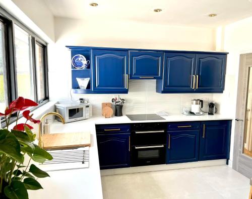 a blue kitchen with white counters and blue cabinets at Fairways Villa Newcastle in Newcastle