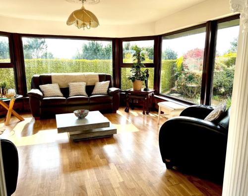 a living room with leather furniture and large windows at Fairways Villa Newcastle in Newcastle