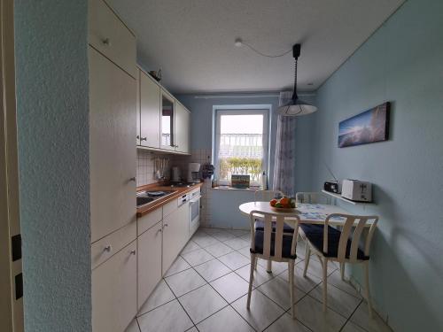 a kitchen with a table and chairs and a window at Ferienwohnung Residenz am Sandstrand Norddeich in Norden