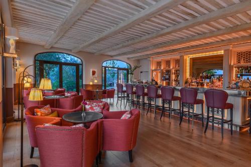 a restaurant with red chairs and a bar at Coquillade Provence - Relais & Châteaux in Gargas