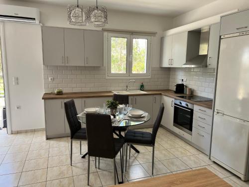 a kitchen with a table and chairs in a kitchen at Porfyra Apartment Portoheli in Porto Heli