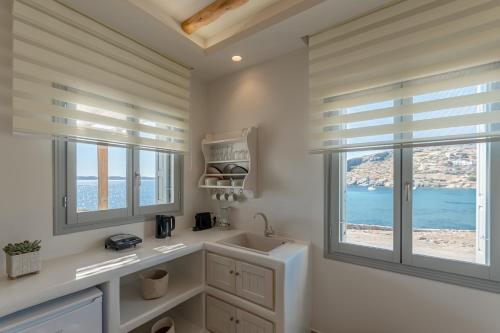 a bathroom with a sink and two windows at Porto Dema Luxury Suites in Schinoussa