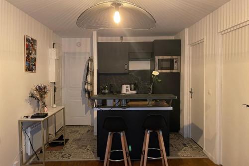 une cuisine avec deux tabourets de bar devant un comptoir dans l'établissement 42m close to Montmartre, à Paris