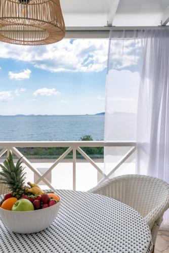 a bowl of fruit sitting on a table in front of the ocean at Grand Bleu Anastazia in Porto Heli