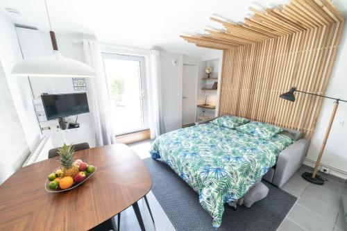 een slaapkamer met een bed en een tafel met een fruitschaal bij Studio JACQUARD avec terrasse-Oullins centre-Lyon in Oullins