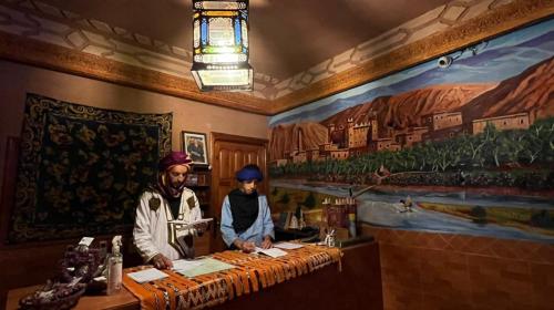mężczyzna i kobieta stojący przy ladzie w restauracji w obiekcie Kasbah La Famille Berbère w mieście Boumalne Dades