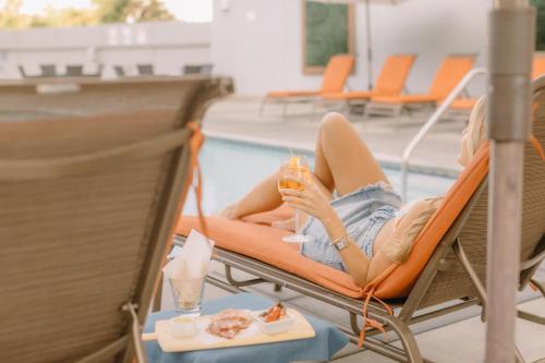 Eine Frau auf einem Stuhl am Pool mit einem Drink in der Unterkunft San Jose Marriott in San Jose