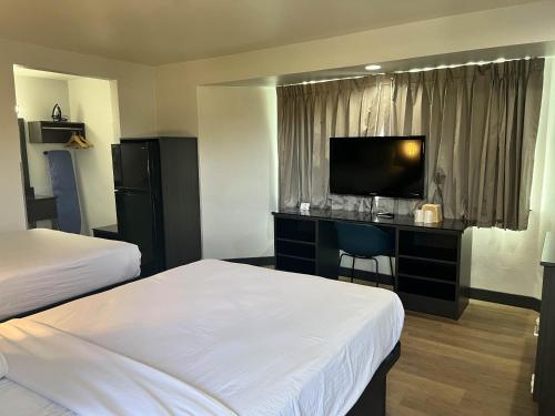 a hotel room with two beds and a desk with a television at Suites Escondido CA in Escondido