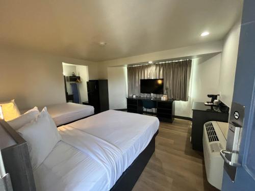 a hotel room with two beds and a flat screen tv at Suites Escondido CA in Escondido