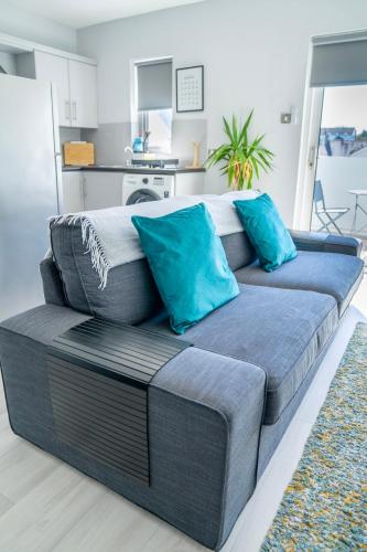 a gray couch with blue pillows in a living room at Causeway Coast Beach Front Apartment - Ballycastle in Ballycastle