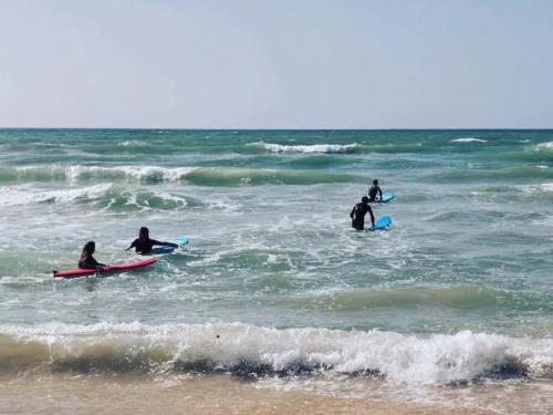 a group of people sitting on surfboards in the ocean at Jaffa Seaside House in Tel Aviv