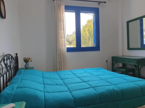 a blue bed in a bedroom with a window at Sunset Holiday House in Archangelos