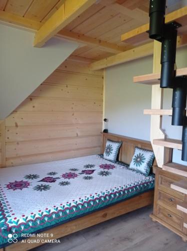 a bed in a room with a wooden ceiling at Pokoje ,,Goramiba''Jurgów in Jurgów