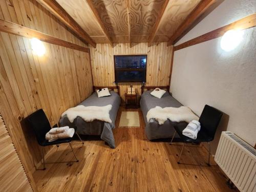 a room with two beds and two chairs in it at Hostal Hunter in Puerto Montt
