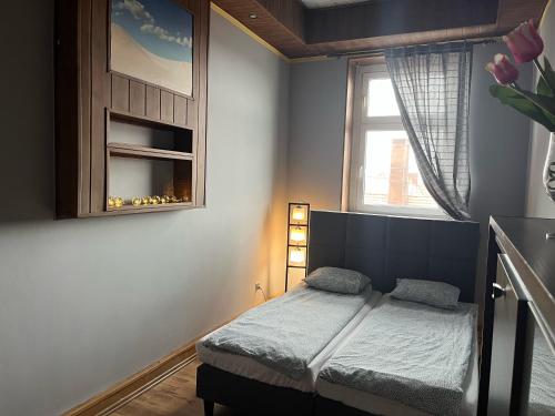 a small bedroom with a bed and a window at Apartament Centrum-Zwycięstwa in Gliwice