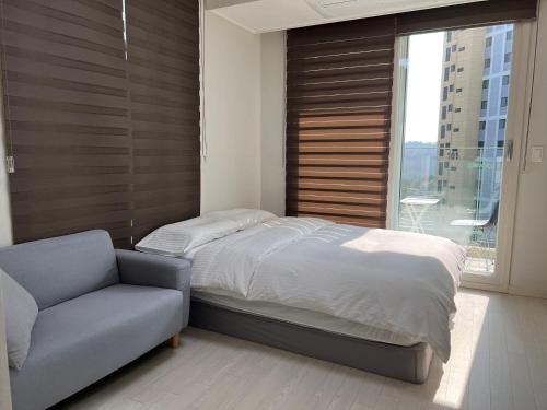 1 dormitorio con cama, sofá y ventana en THE TiME en Incheon