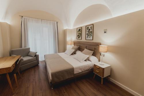 a bedroom with a bed and a chair and a desk at Olivae Hostal Boutique in Cáceres