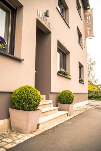 a building with stairs and potted plants in front of it at Mandarina Hotel Luxembourg Strassen in Luxembourg