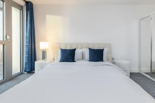 a bedroom with a large white bed with blue pillows at Right Place in London