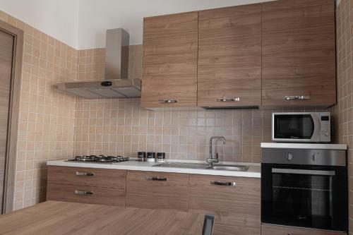 uma cozinha com armários de madeira, um lavatório e um micro-ondas em L'Affresco Affittacamere em Campolattaro