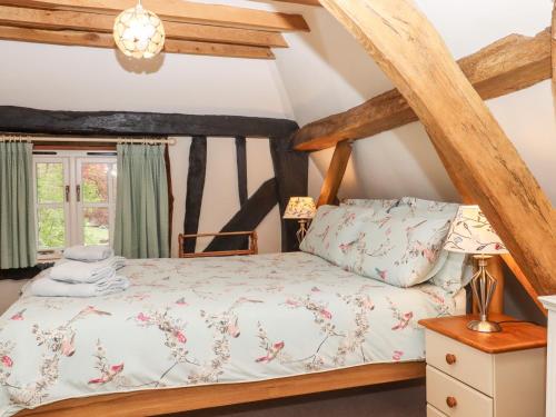 a bed in a room with wooden beams at Wren Cottage in Canterbury