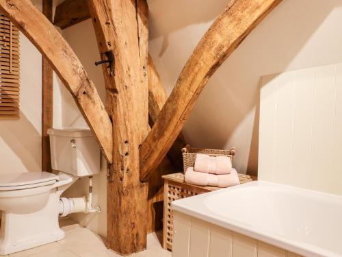 a bathroom with wooden beams and a toilet and a tub at Wren Cottage in Canterbury