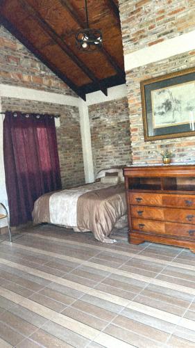 a bedroom with a bed and a dresser and a brick wall at Cabaña en Rancho los reyes in Tijuana