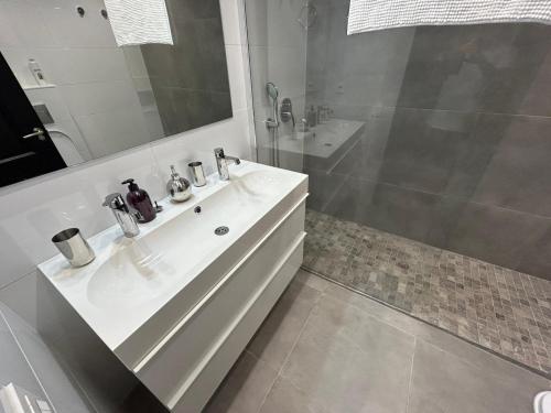 La salle de bains blanche est pourvue d'un lavabo et d'une douche. dans l'établissement Enjoy Spain - La Maestranza, à Marbella