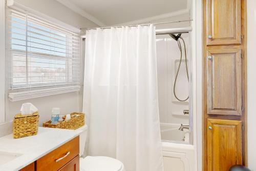 a bathroom with a white shower curtain and a toilet at Assateague Pointe - Yardarm in Berlin