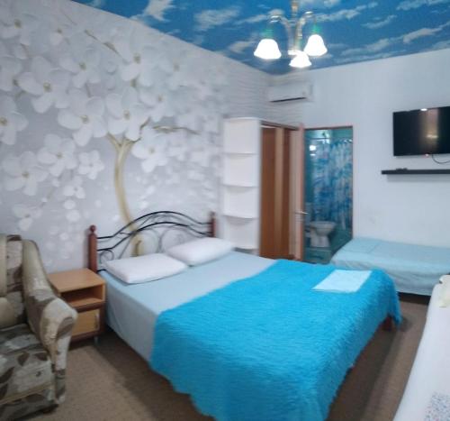 a bedroom with a bed with a tree painted on the wall at Гостевой дом ЛОНТАНА in Gagra