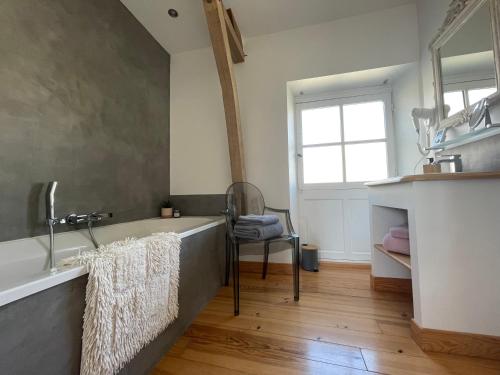 a bathroom with a tub and a chair and a window at Coté jardin in Sainte-Suzanne