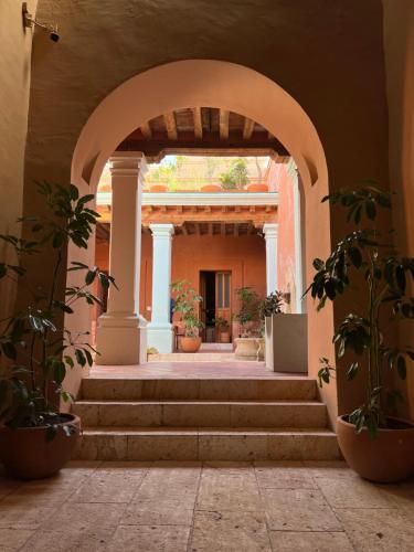 une arche avec des escaliers dans un bâtiment avec des plantes en pot dans l'établissement Jr-Kiyo Estudios, à Oaxaca