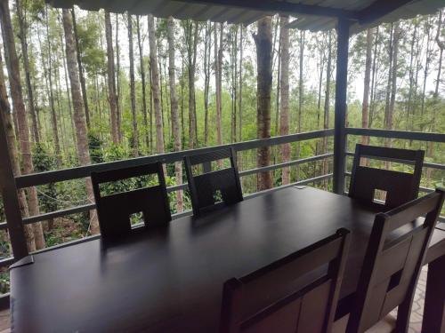 a table and chairs on a porch with a view of trees at Cholai Resorts & Hotels in Yercaud