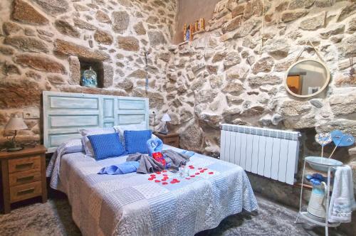 - une chambre avec un lit et un mur en pierre dans l'établissement casa rural La Cuadra, à Villar de Corneja