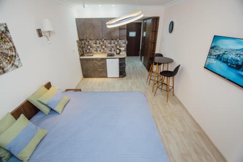 a bedroom with a large blue bed and a kitchen at Real Beach Tower in Batumi
