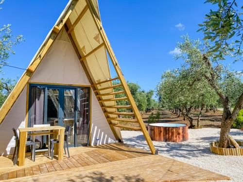 una piccola casa con una terrazza in legno e una scala di A-luxury Glamping by La Mignola a Fasano