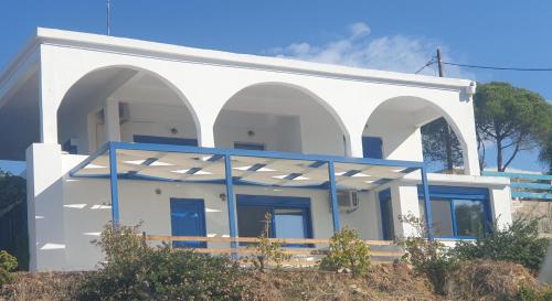 a white building with blue doors and windows at Sunset Holiday House in Archangelos