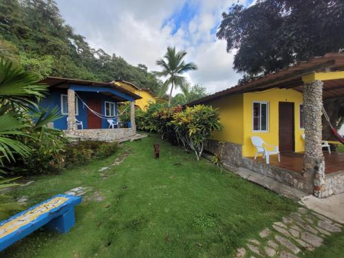 a yellow and blue house with a bench in the yard at ScubaPortobelo in Portobelo